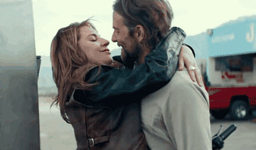 Two characters embracing and smiling, from the film "A Star Is Born."