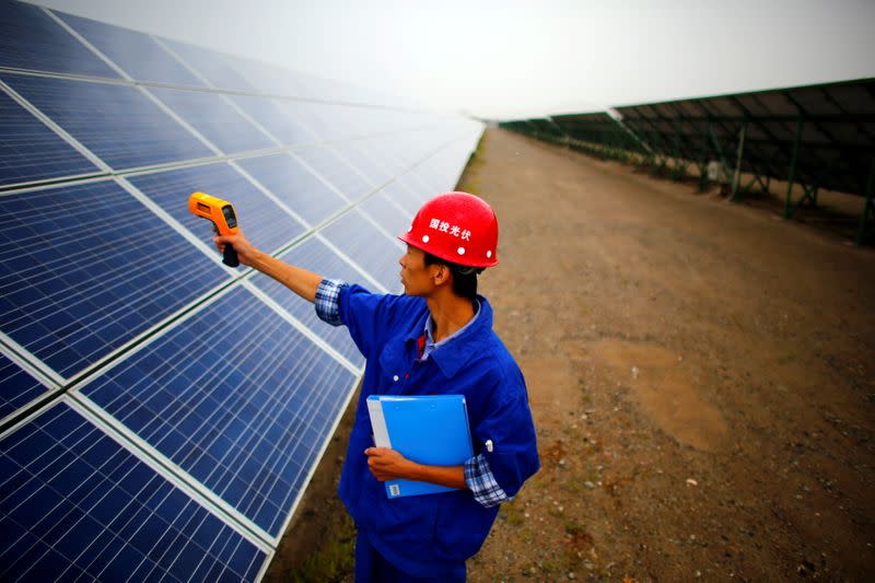 FILE PHOTO: A worker inspects solar panels at a solar farm in Dunhuang