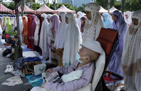 A Muslim domestic helper attend Eid al-Fitr prayers to mark the end of the holy fasting month of Ramadan with an old person in Taipei ,Taiwan June 25,2017. REUTERS/Tyrone Siu