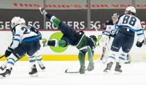 Vancouver Canucks left wing Nils Hoglander (36) falls to the ice after being checked by Winnipeg Jets defenseman Neal Pionk (4) during first-period NHL hockey game action in Vancouver, British Columbia, Sunday, Feb. 21, 2021. (Jonathan Hayward/The Canadian Press via AP)
