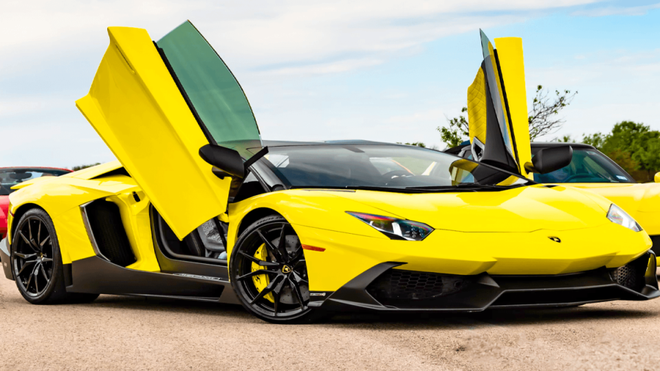 A yellow Lamborghini with its doors open.