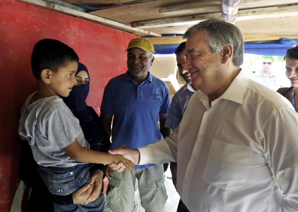 FILE- In this June 19, 2016 file photo, United Nations High Commissioner for Refugees Antonio Guterres shakes hands with a Syrian child during his visit to Khaldeh, south of Beirut, Lebanon. Guterres takes the reins of the United Nations on New Year's Day, promising to be a "bridge-builder" but facing an antagonistic incoming U.S. administration led by Donald Trump who thinks the world body's 193 member states do nothing except talk and have a good time. (AP Photo/Bilal Hussein, File)