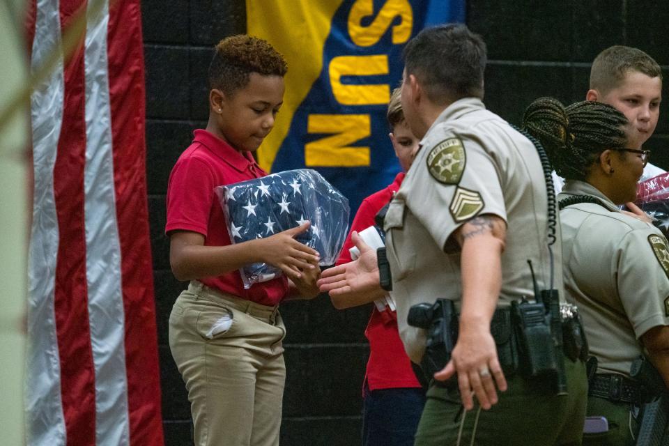 Ossun Elementary fifth-grader Draven Holeman is congratulated on stage with two fellow students being commended for their flag-raising service by Lafayette Parish Sheriff Deputies and presented with an American flag by state representatives Friday, May 20, 2022.