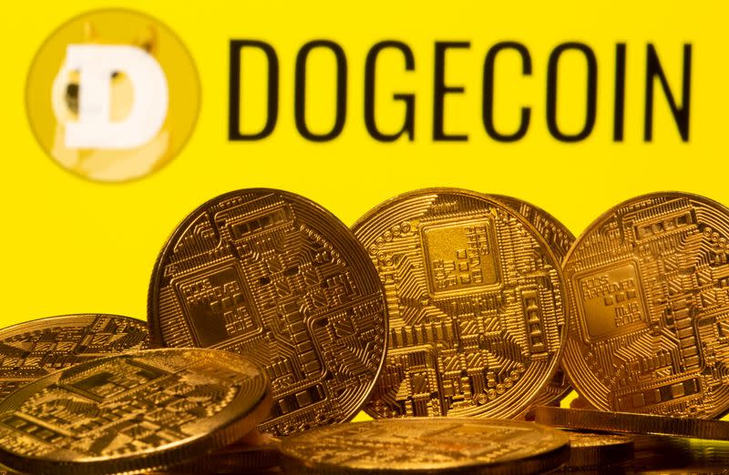 FILE PHOTO: Cryptocurrency representations are seen in front of the Dogecoin logo in this illustration