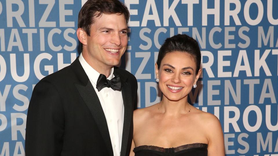 Mila Kunis and Ashton Kutcher on a red carpet, smiling