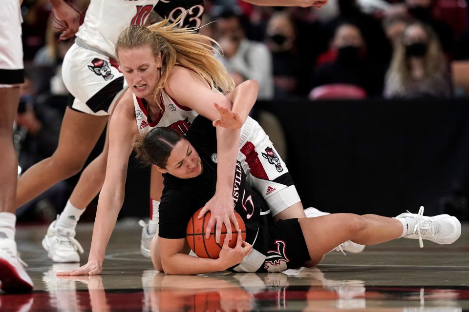 NC State center Elissa Cunane, top, and Louisville guard Mykasa Robinson (5) chase the ball during the first half of Thursday's game.