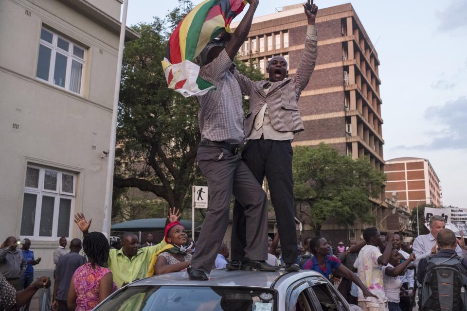 Zimbabweans shout slogans and dance on top of a car.