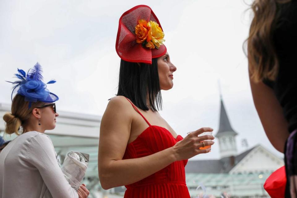 Wearing bright red, Shea Leparoux watches an early race featuring her husband, jockey Julien Leparoux, during Kentucky Derby 150 at Churchill Downs in Louisville, Ky., Saturday, May 4, 2024.