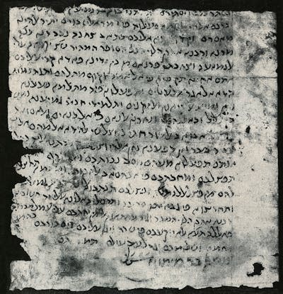 A black and white image of an old, worn parchment covered in letters in black ink.