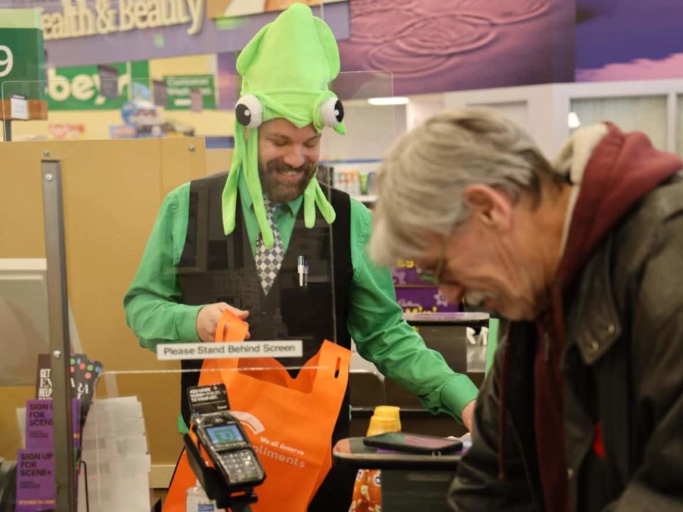 Jason Rutledge packs groceries for a customer at an Edmonton Sobeys in the 'slow social lane,' a check-out lane for people who want to take their time and have a bit of a chat while they buy their groceries.   (Kory Siegers/CBC - image credit)