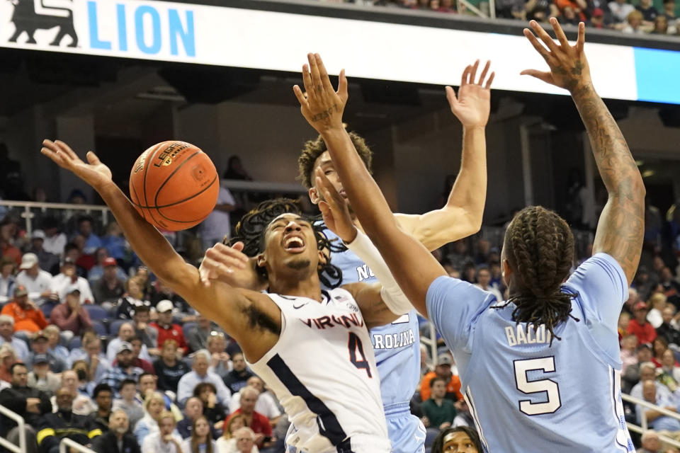 Virginia guard Armaan Franklin (4) is fouled as he drives between North Carolina forward Armando Bacot (5) and forward Pete Nance during the first half of an NCAA college basketball game at the Atlantic Coast Conference Tournament in Greensboro, N.C., Thursday, March 9, 2023. (AP Photo/Chuck Burton)