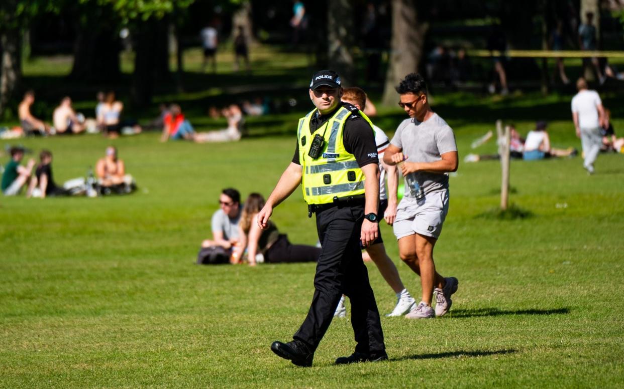 Police Scotland officer walking among large numbers of sunbathers gathered at The Meadows close to the centre of Edinburgh last weekend - Stuart Nicol