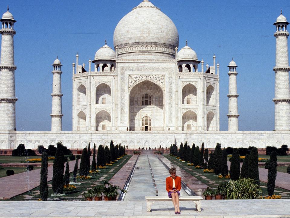 Diana, Princess of Wales, wearing a red and purple suit designed by Catherine Walker, poses alone outside the Taj Mahal on February 11, 1992 in Agra, India.