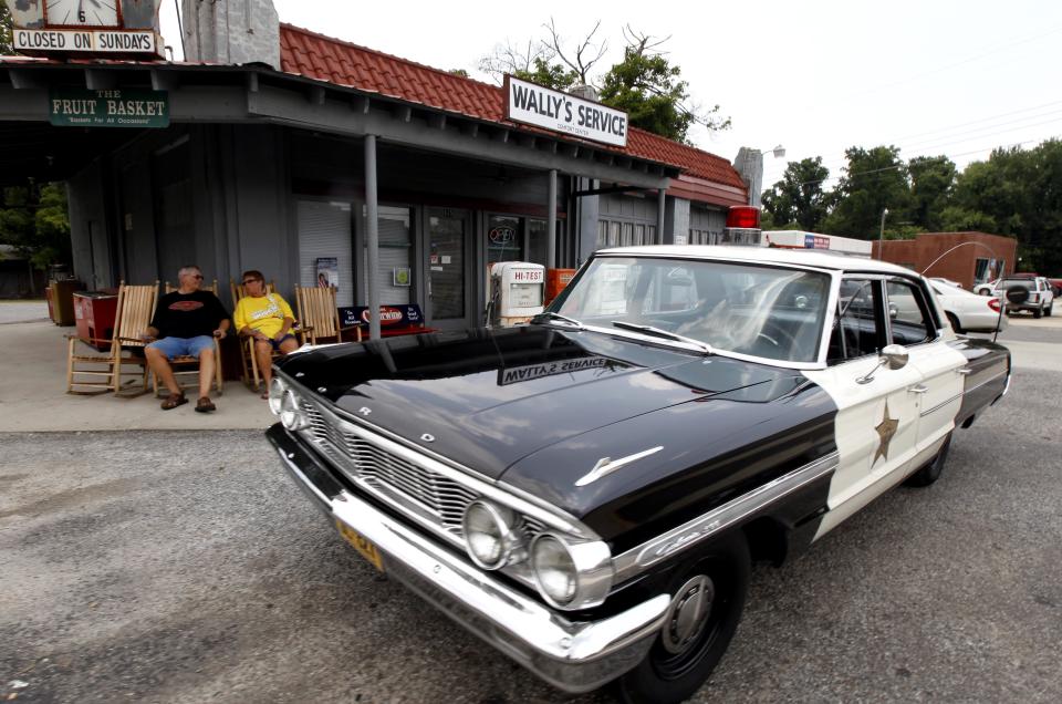 FILE - This July 3, 2012 file photo shows Mike and Terry Jones sitting outside Wally's Service, a replica of the Andy Griffith Show, in Mount Airy, N.C. Tourism in Mount Airy is up since Andy Griffith died July 3, with about 10,400 people visiting the Andy Griffith Museum in July, almost double the 5,400 who visited in July 2011. (AP Photo/Gerry Broome, file)