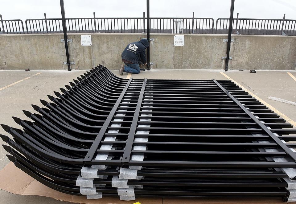 Wyatt Varner, an employee of Central Fence LLC of Vienna, attaches a barrier post to the ninth floor of the Fifth and Walnut municipal parking garage on Friday.