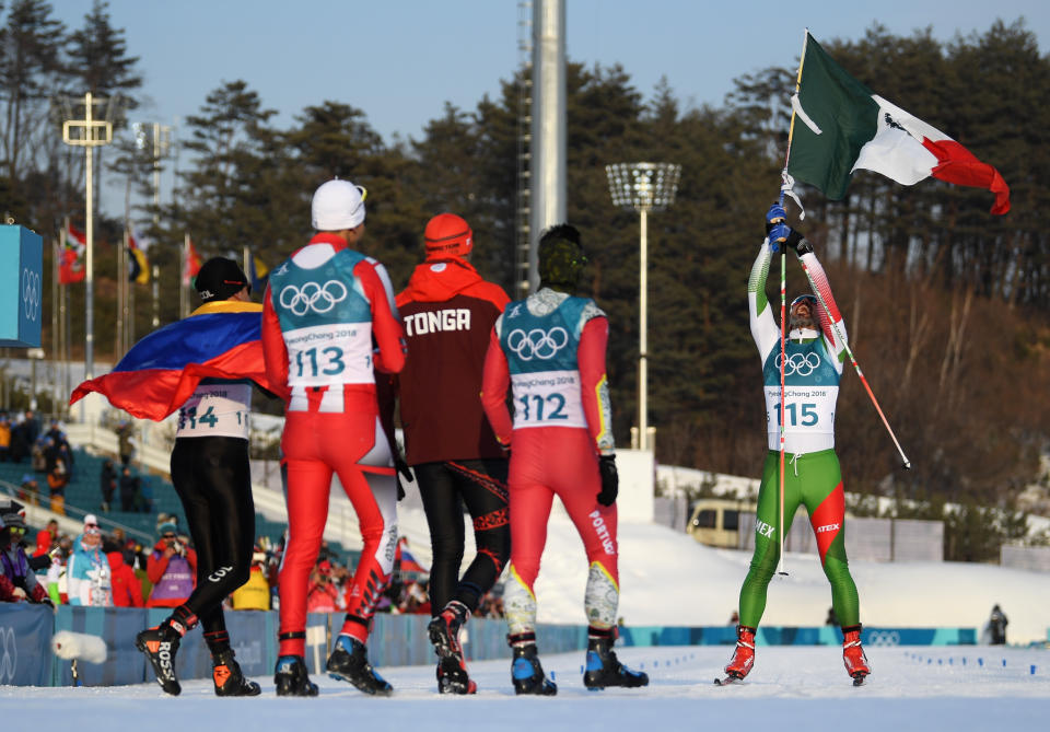 PYEONGCHANG-GUN, SOUTH KOREA – FEBRUARY 16: German Madrazo of Mexico holds the flag of Mexico as he crosses the finish line as Sebastian Uprimny of Colombia, Samir Azzimani of Morocco, Pita Taufatofua of Tonga and Kequyen Lam of Portugal look on during the Cross-Country Skiing Men’s 15km Free event. (Getty Images)