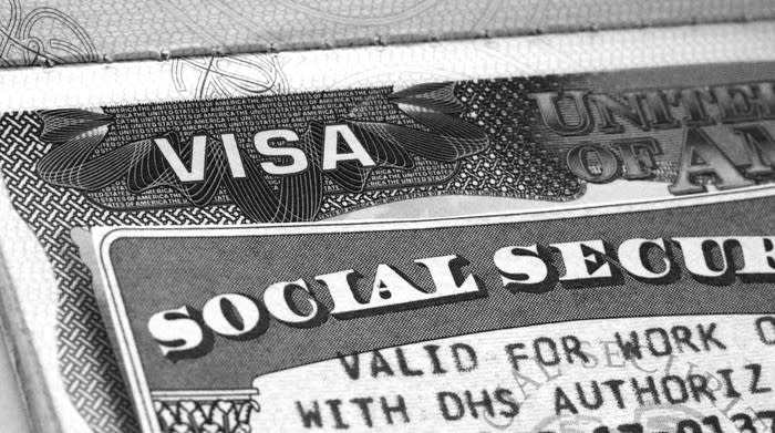 A Social Security card lying atop a work visa.