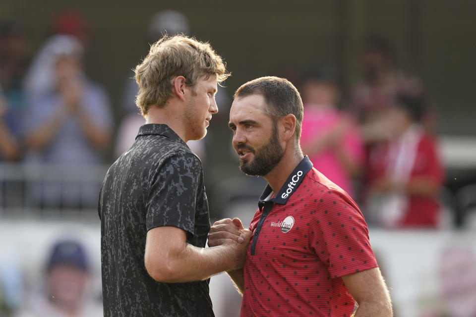 Cam Davis of Australia, left, shakes hands with Troy Merritt after winning in the fifth playoff hole in the final round of the Rocket Mortgage Classic golf tournament, Sunday, July 4, 2021, at the Detroit Golf Club in Detroit. (AP Photo/Carlos Osorio)