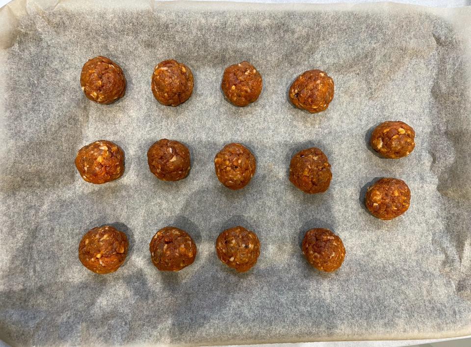 14 small meatballs rolled out onto a lined baking tray