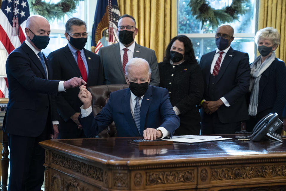 President Joe Biden hands a pen to Homeland Security Secretary Alejandro Mayorkas as he signs an executive order to improve government services, in the Oval Office of the White House, Monday, Dec. 13, 2021, in Washington. (AP Photo/Evan Vucci)
