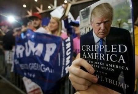 A supporter holds up a book to be signed by U.S. Republican presidential candidate Donald Trump at a campaign rally in Cleveland, Ohio March 12, 2016. REUTERS/Aaron Josefczyk EDITORIAL USE ONLY. NO RESALES. NO ARCHIVE