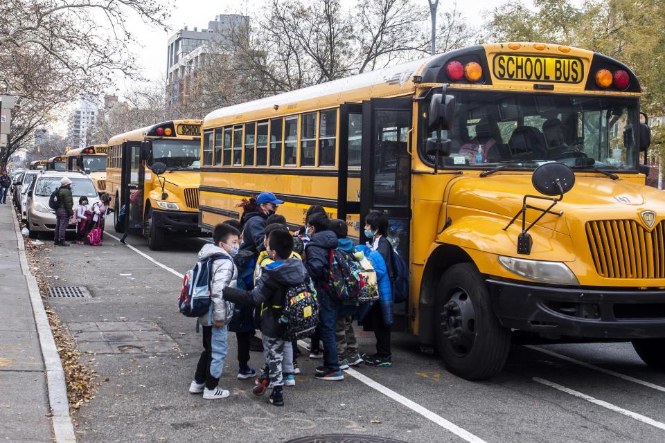 FILE — Students wearing masks board a school bus outside New Explorations into Science, Technology and Math school, in the Lower East Side neighborhood of New York, Dec. 21, 2021. In a reversal, New York Mayor Eric Adams is considering a remote option for schools. (AP Photo/Brittainy Newman, File)