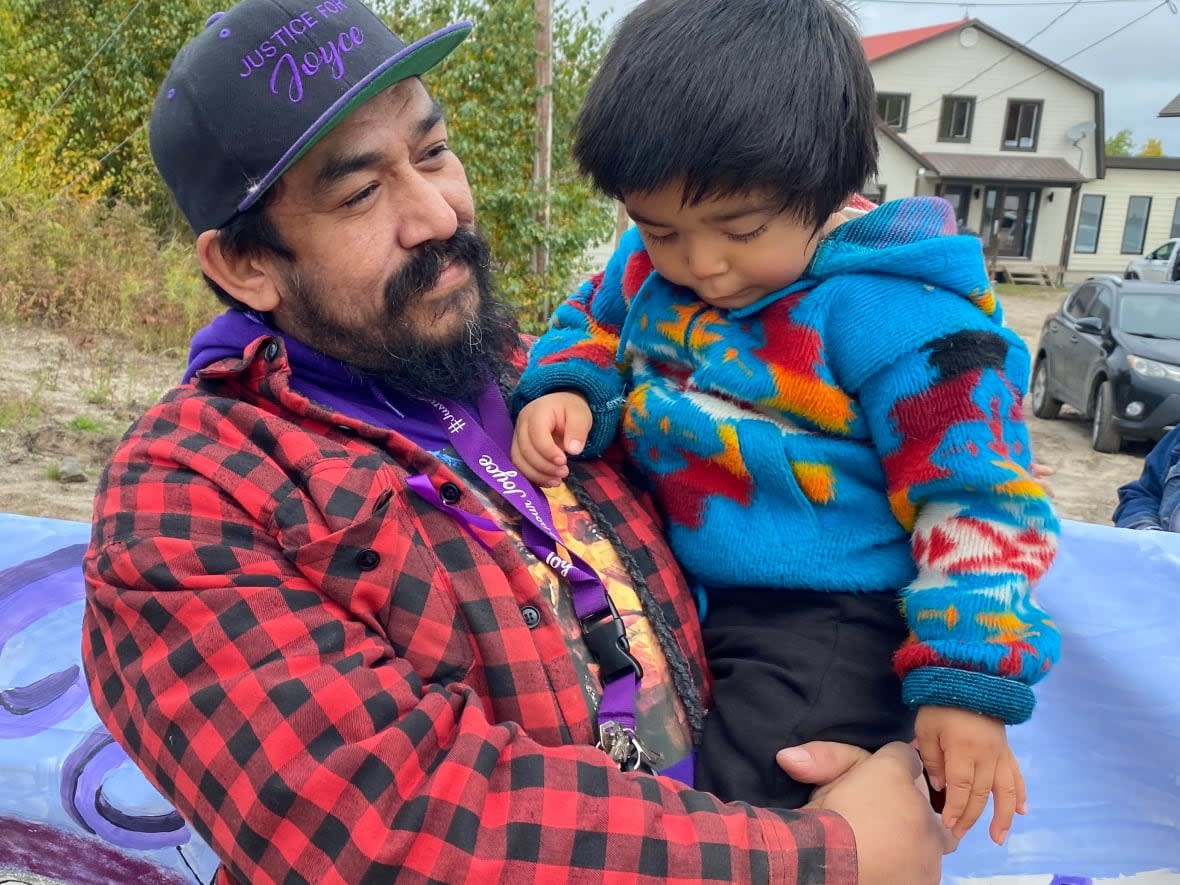 The husband of the late Joyce Echaquan, Carol Dubé, held the youngest of their seven children, Carol Jr., during a march in Manawan on Wednesday to commemorate Echaquan, two years after her death. (Marie-Laure Josselin/Radio-Canada - image credit)