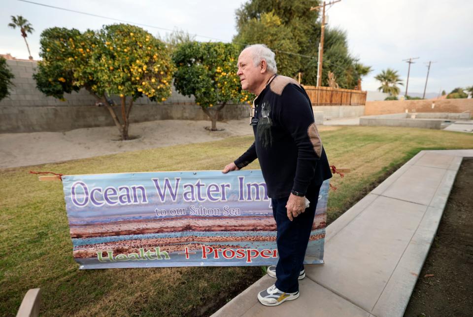 Chuck Parker, an advocate for a water pipeline from the Sea of Cortez to the Salton Sea, moves a sign to pose for a photo in the backyard of his home in Bermuda Dunes, California, on Monday, Dec. 11, 2023. | Kristin Murphy, Deseret News