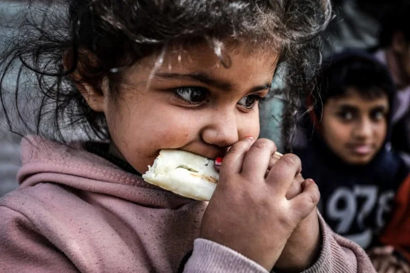 An internally displaced Palestinian girl eats a piece of bread at a temporary camp in the southern Gaza Strip city of Rafah. Abed Rahim Khatib/dpa