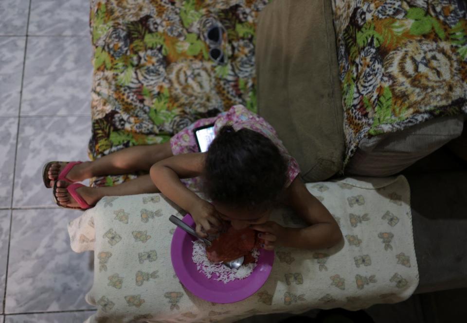 Izabela, 2, eats a meal made from food found in a garbage container by her mother Carla (Reuters)