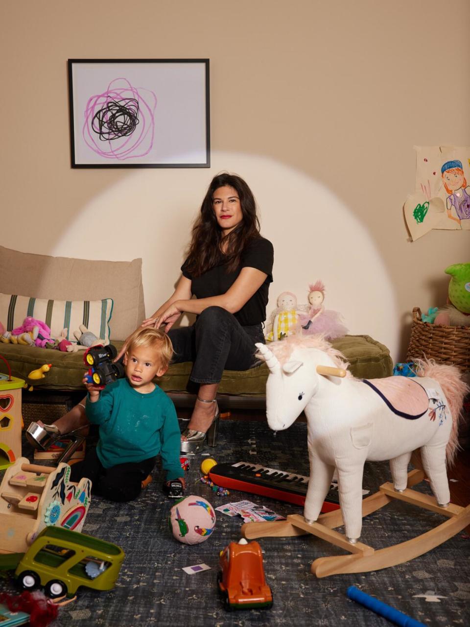 Joanna Calo sits in a playroom surrounded by her toddler and his toys.