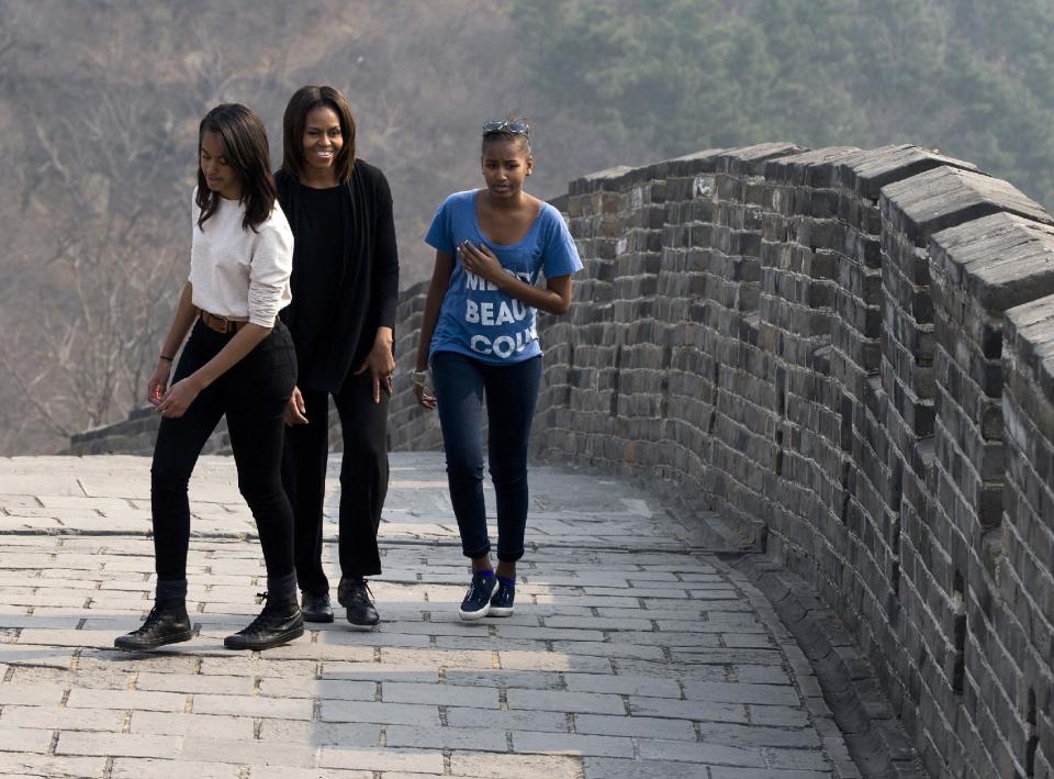 FILE - This March 23, 2014 file photo shows first lady Michelle Obama walking with her daughters Malia, left, and Sasha, right, as they visit the Mutianyu section of the Great Wall of China in Beijing. When President Barack Obama travels abroad, getting just the leader of the free world doesn’t seem to be enough. Countries want the first lady, too. But Michelle Obama won’t join her husband when he heads to Asia next week and her absence is likely to sting, especially in Japan. It’s the first of four countries on Obama’s travel schedule and the only one welcoming him on an official state visit. (AP Photo/Andy Wong, File)