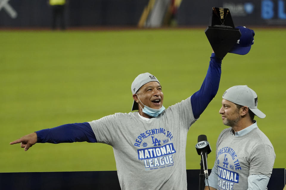 Los Angeles Dodgers manager Dave Roberts, left, and President of Baseball Operations Andrew Friedman celebrate with the trophy after winning Game 7 of a baseball National League Championship Series against the Atlanta Braves Sunday, Oct. 18, 2020, in Arlington, Texas. (AP Photo/Eric Gay)