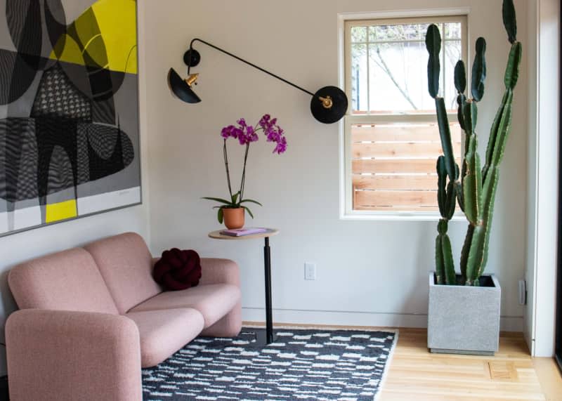 Multi-armed wall lamp in room with pink love seat.