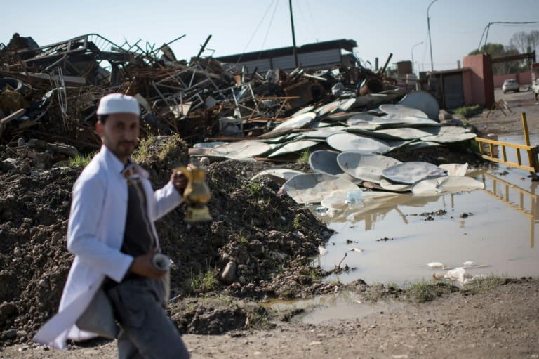 An Iraqi coffee seller walks past smashed satellite dishes in east Mosul on April 15, 2017, the legacy of the Islamic State group's tyrannical two and a half years in control