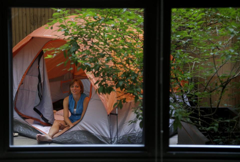 Kathleen Boyle poses for a picture in a tent on the patio of her room at the Affina Hotel in New York, Thursday, Aug. 15, 2013. A couple of New York City locales are offering an unusual option _ the chance to sleep outdoors, incredibly comfortably. It’s an urban take on “glamping,” where hotel comforts are taken outside. (AP Photo/Seth Wenig)