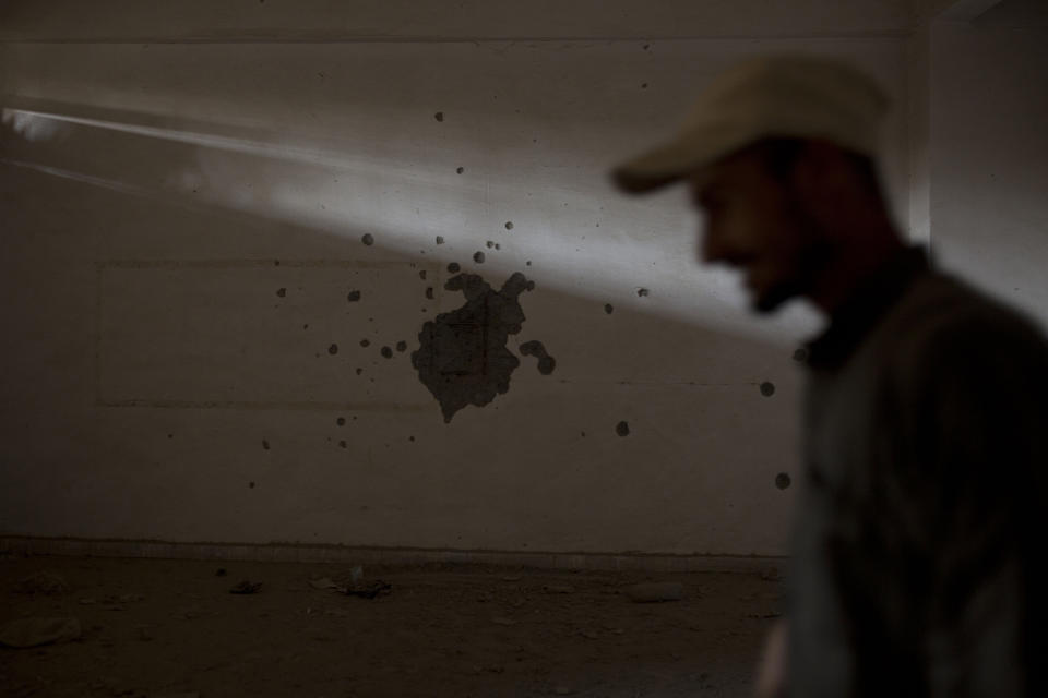 In this Thursday, Sept. 5, 2019, photo, a guard walks through the room where Islamic State militants executed their prisoners in a sprawling, makeshift prison in the basement of the stadium in Raqqa, Syria. Two years after the military offensive to oust IS from its stronghold, Raqqa has been picking up the pieces. (AP Photo/Maya Alleruzzo)