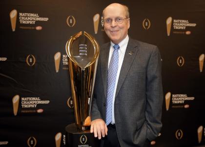 College Football Playoff Executive Director Bill Hancock poses with the College Football Playoff National Championship Trophy in Irving, Texas. (AP Photo/Tony Gutierrez, File)