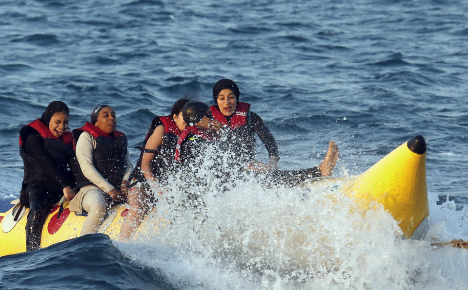 FILE - In this July 26, 2019 file photo, holiday-makers ride a banana boat at al Sokhna beach in Suez, Egypt. The burkini, a swimsuit worn by conservative Muslims to cover the entire body, is scorned in many upper class Egyptian circles where it and the headscarf is seen as lower class. Women who wear the burkini or headscarves can face discrimination in upper-class beach resorts or in bars or clubs, though across Egypt the majority of women wear conservative dress. (AP Photo/Amr Nabil, File)