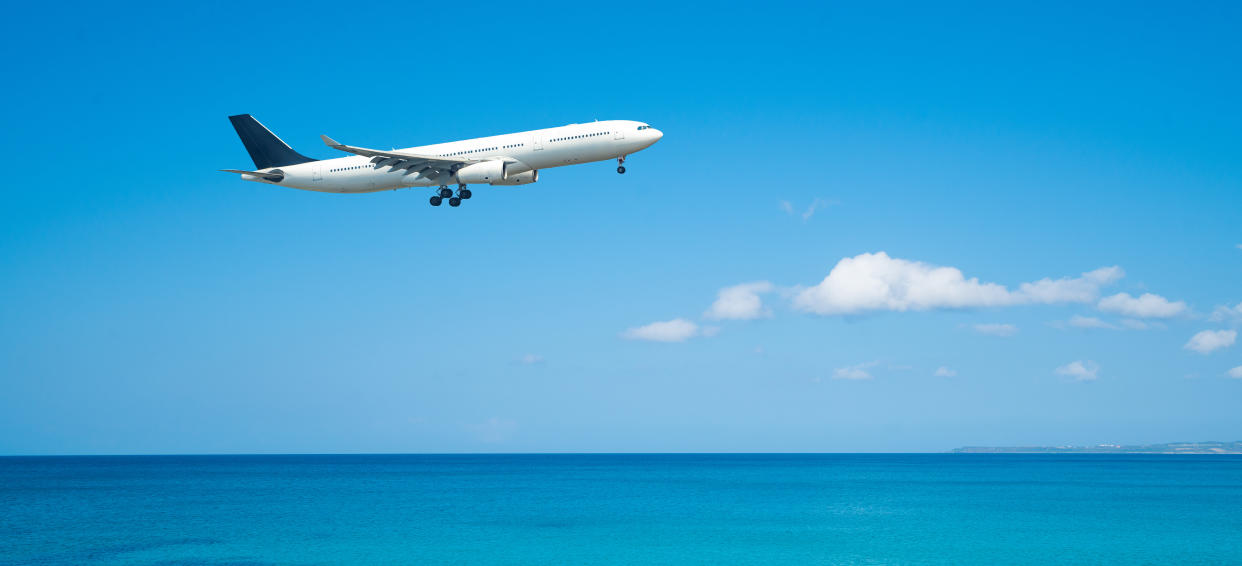 Commerical Airplane Flying with blue sky and beach background
