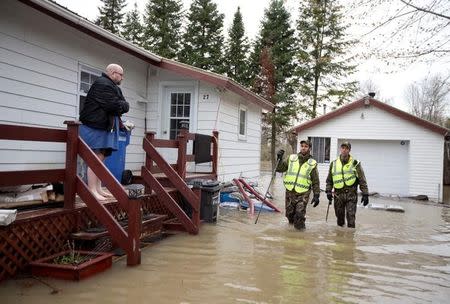 Surete du Quebec Police officers try to convince a resident to evacuate his home in a flooded residential neighbourhood in Rigaud, Quebec, Canada May 7, 2017. REUTERS/Christinne Muschi