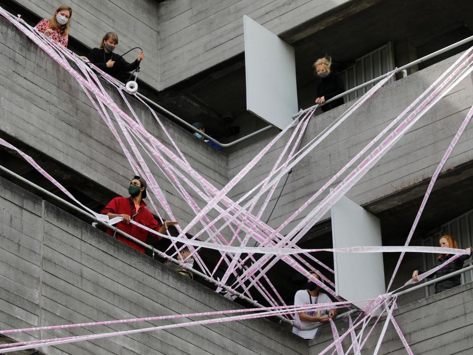 Volunteers from the #MissingLiveTheatre initiative wrap pink tape reading "missing live theatre" on the National Theatre, 3 July, 2020: AFP via Getty Images