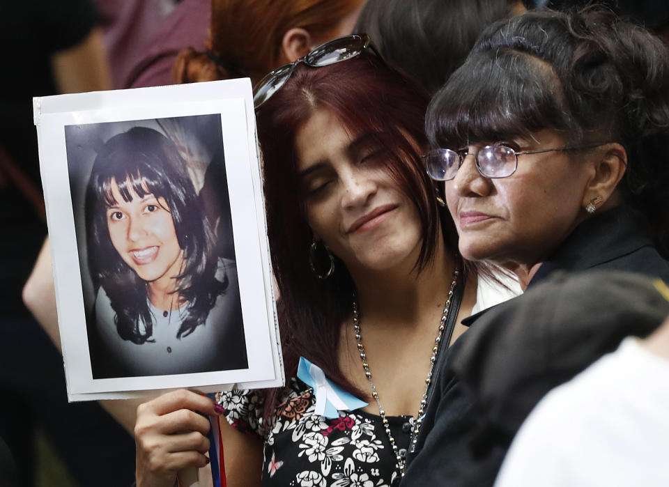 FILE - In this Sept. 11, 2016, file photo, mourners hold a photo of their loved one during the 15th anniversary of the attacks of the World Trade Center at the National September 11 Memorial in New York. The coronavirus pandemic has reshaped how the U.S. is observing the anniversary of 9/11. The terror attacks' 19th anniversary will be marked Friday, Sept. 11, 2020, by dueling ceremonies at the Sept. 11 memorial plaza and a corner nearby in New York. (AP Photo/Mary Altaffer, File)