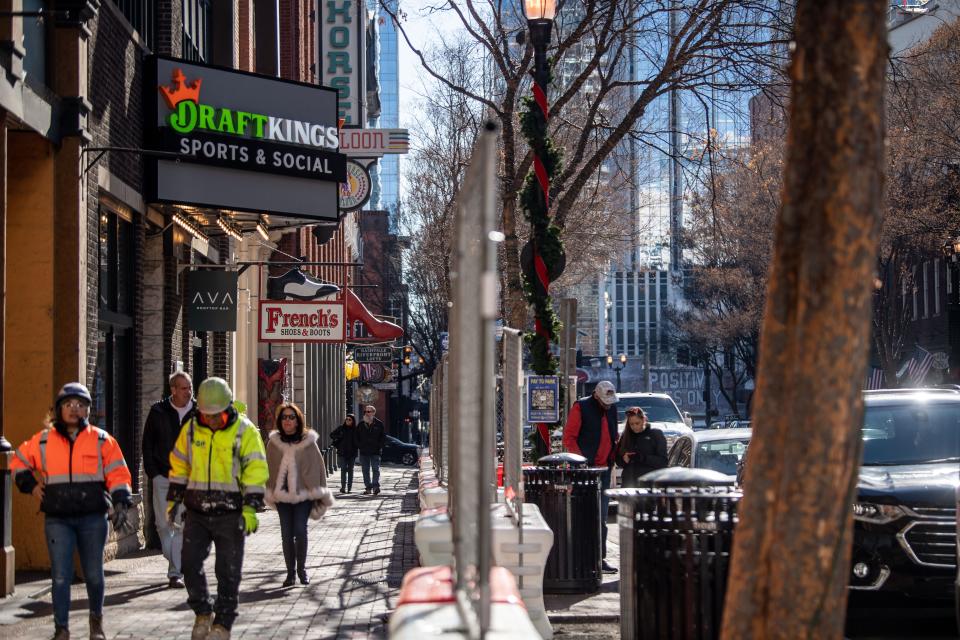 Pedestrians and construction workers walk along 2nd Avenue passing the local business in Nashville, Tenn., Tuesday, Dec. 19, 2023.