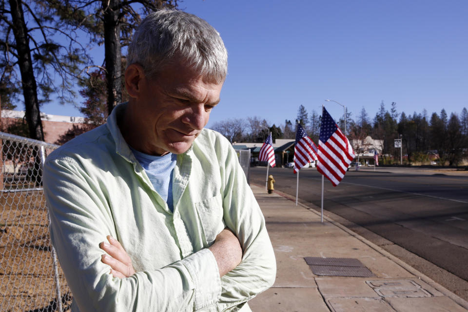 Robert Bean pauses after passing flags lining the streets Friday, Nov. 8, 2019 in Paradise, Calif., placed in remembrance of last year's Camp Fire. Friday marks the one year anniversary of the wildfire that nearly destroyed the entire town. Bean's house survived the fire.(AP Photo/Rich Pedroncelli)