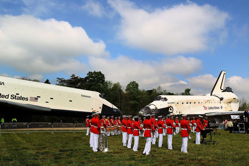 A military band plays as the Space Shuttle Discovery (R), and the Space Shuttle Enterprise (L), sit nose to nose, during an event at the Smithsonian National Air and Space Museum Steven F. Udvar-Hazy Center April 19, 2012 in Chantilly, Virginia. The space shuttle Discovery is the he oldest and most traveled vehicle from NASA's space shuttle program, and will replace the Interprise at the museum. (Photo by Mark Wilson/Getty Images)