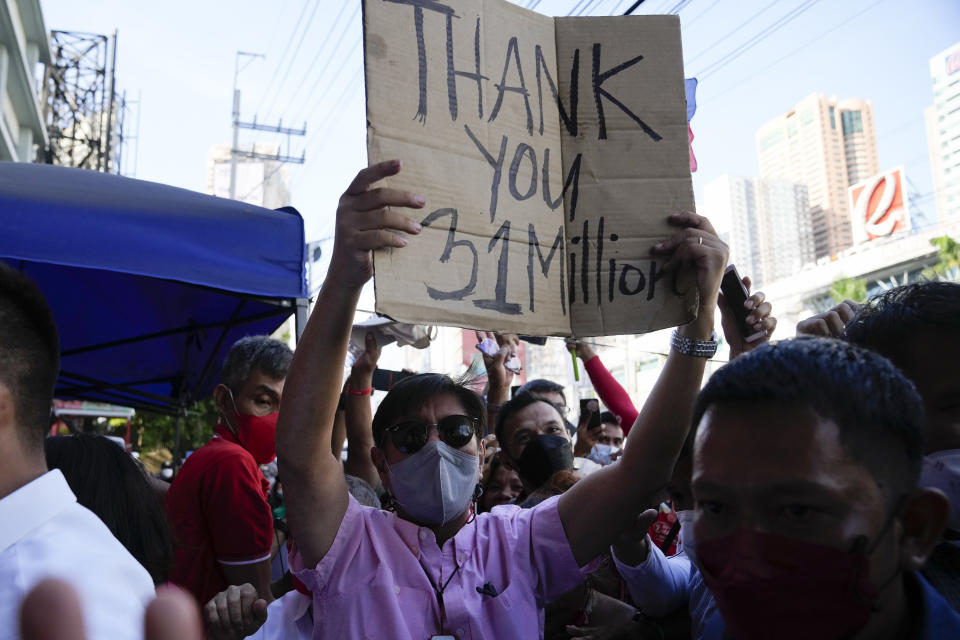 Presidential candidate Ferdinand "Bongbong" Marcos Jr. holds a sign he got from the crowd as he celebrates outside his headquarters in Mandaluyong, Philippines on Wednesday, May 11, 2022. Marcos' apparent landslide victory in the Philippine presidential election is raising immediate concerns about a further erosion of democracy in Asia and could complicate American efforts to blunt growing Chinese influence and power in the Pacific. (AP Photo/Aaron Favila)