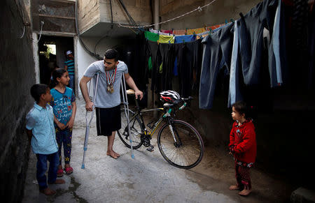 Palestinian cyclist Alaa Al-Daly, 21, who lost his leg by a bullet fired by Israeli troops, talks with his sister while holding his bicycle at his house in Rafah, southern Gaza Strip, April 18, 2018. REUTERS/Suhaib Salem