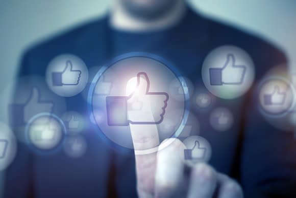 A man pressing an illustrated thumbs up icon, representing a "like" on Facebook.