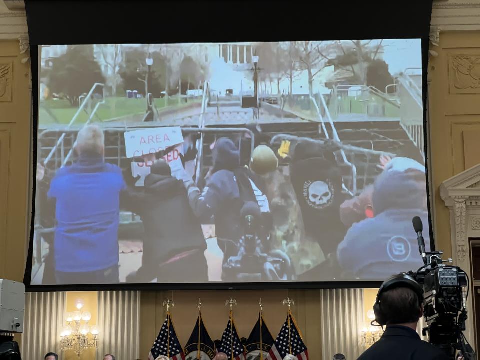 A video screen shows rioters breach the barrier knocking down Capitol Police Officer Caroline Edwards